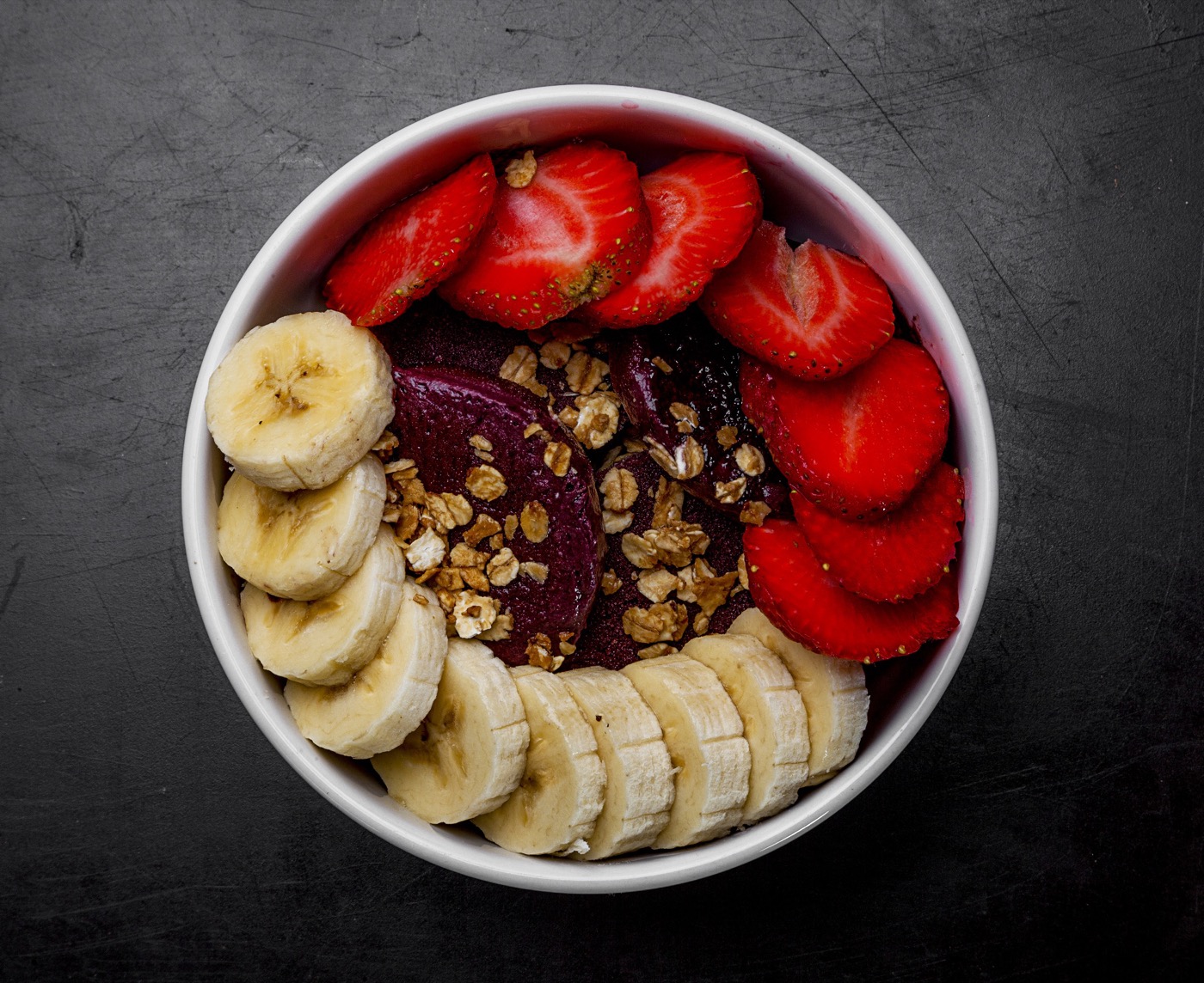 Taça de açaí coberta com morangos, banana e granola